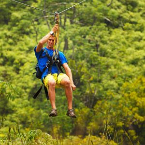 Man on Zipline over Lush Tropical Valley